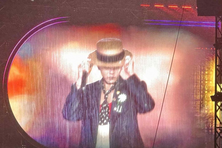 G-Dragon chọn phong cách quen thuộc của anh, với blazer dáng rộng, mũ cói boater cùng bông hoa cúc thiếu cánh trên ngực. Dưới làn mưa như trút, anh cùng hàng nghìn khán giả hát vang các bản hit.