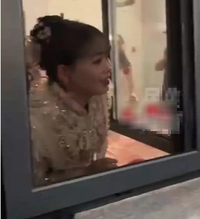 Cô dâu ngó ra cửa sổ khuyên chú rể làm theo yêu cầu nhưng anh kiên quyết không chịu. Ảnh: Sohu