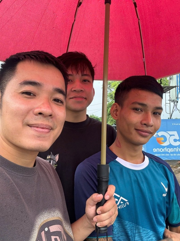 Hiếu (người cầm ô) thấy vui khi có thể lan tỏa việc tốt giữa ngày mưa ngập 