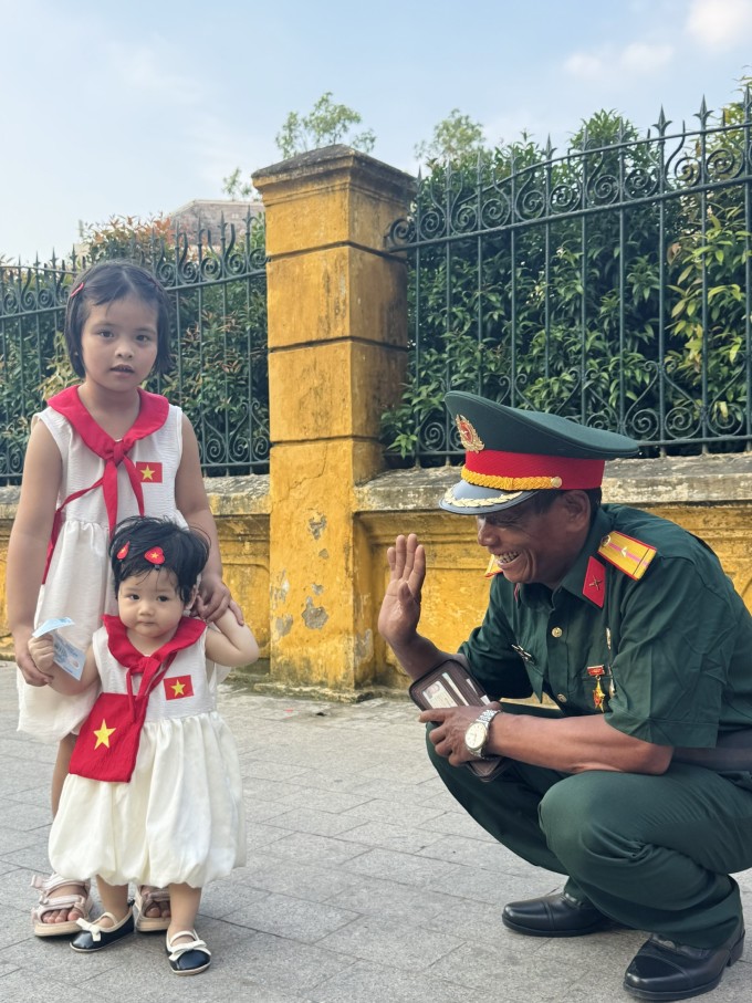 Ông Minh chơi đùa với hai em bé đang chụp ảnh trên phố, ở Ba Đình, Hà Nội, chiều 28/8. Ảnh: Phạm Nga