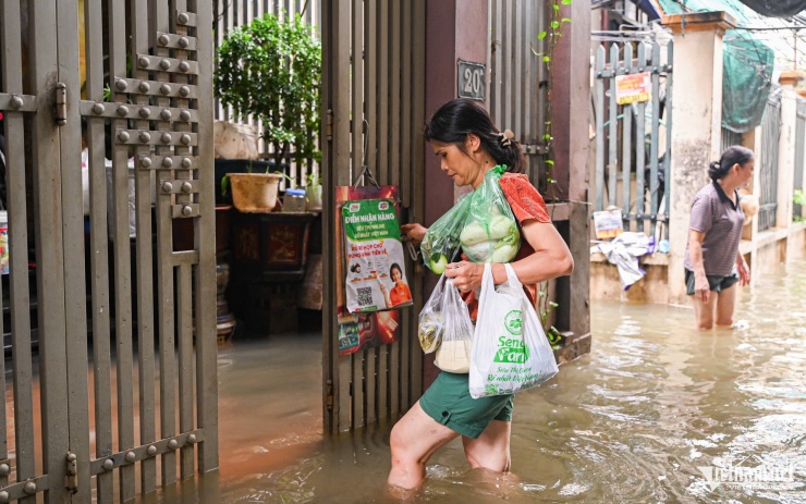 Bà Oanh vượt quãng đường ngập hàng trăm mét để đi làm, đi chợ. Ảnh: Huy Nguyễn