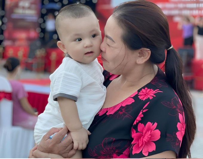 Chị Thêm bế con cháu ngoại, ở quê nhà Hợp Thịnh, năm 2025. Ảnh: Gia đình cung cấp