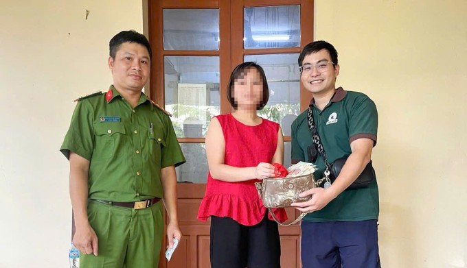 Anh Trung Kiên (bìa phải) trao trả lại chiếc túi cho chị Thu (áo đỏ) tại công an phường Phan Đình Phùng, Thái Nguyên ngày 11/10. Ảnh: Công Minh