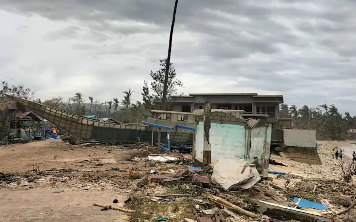 Một chiếc thuyền đánh cá bị sóng đánh dạt vào bờ gần những ngôi nhà trên đảo Calayan, ngày 23/9/2025 (Ảnh: AFP/Cristy Gaffud)