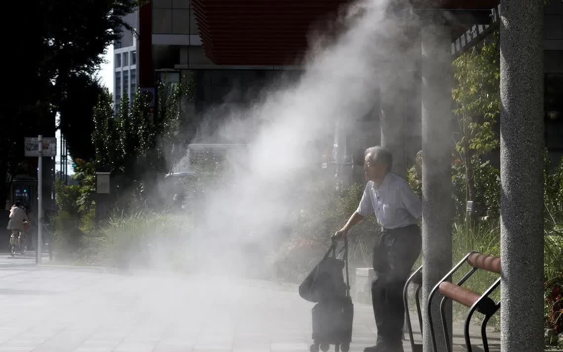 Một người đàn ông lớn tuổi ngồi dưới trạm phun sương làm mát trong đợt nắng nóng ở Tokyo ngày 24/7 (Ảnh: EPA)