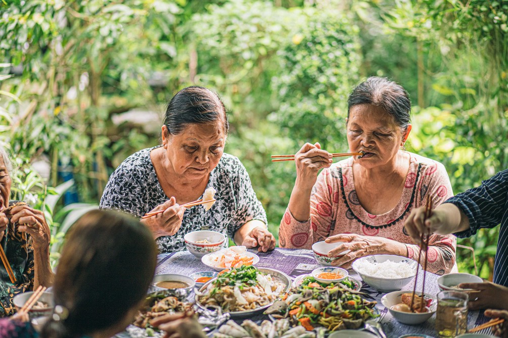 Mọi người quây quần thưởng thức mâm cỗ.
