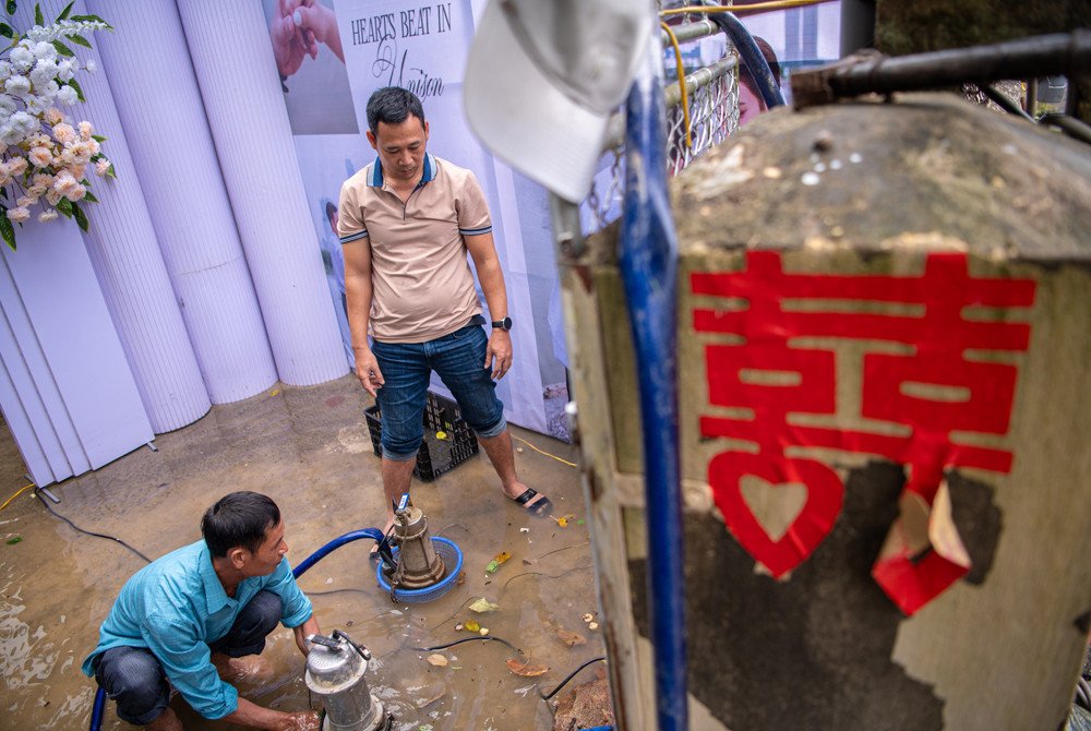 Người nhà chú rể hỗ trợ bơm nước ra khỏi rạp cưới 