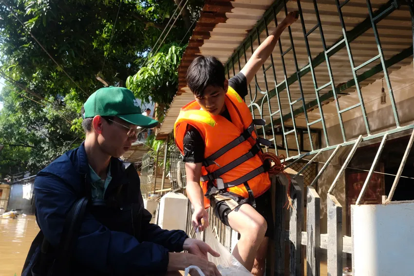 Nước ngập cả con phố và vẫn dâng cao quá nửa tầng một của các ngôi nhà khiến người dân buộc phải chuyển lên sinh hoạt tạm ở tầng hai. Sơn lớn bám hàng rào, rướn người lên để trao từng chai nước.