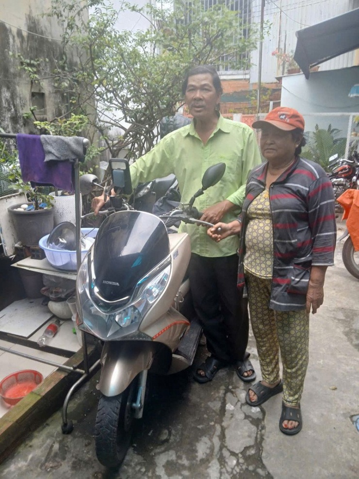 Vợ chồng ông Sơn bên chiếc xe tay ga ông vẫn chạy hàng ngày. Ảnh: NVCC