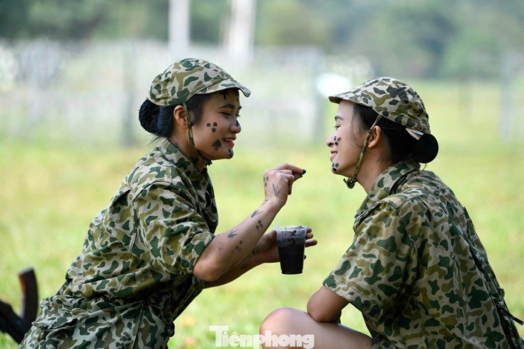 Thượng úy Thùy Dung (bên trái) thực hành kỹ thuật ngụy trang bôi trát cùng đồng đội.